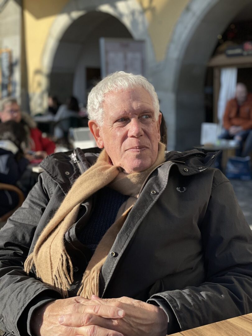 Older man wearing scarf at outdoor cafe