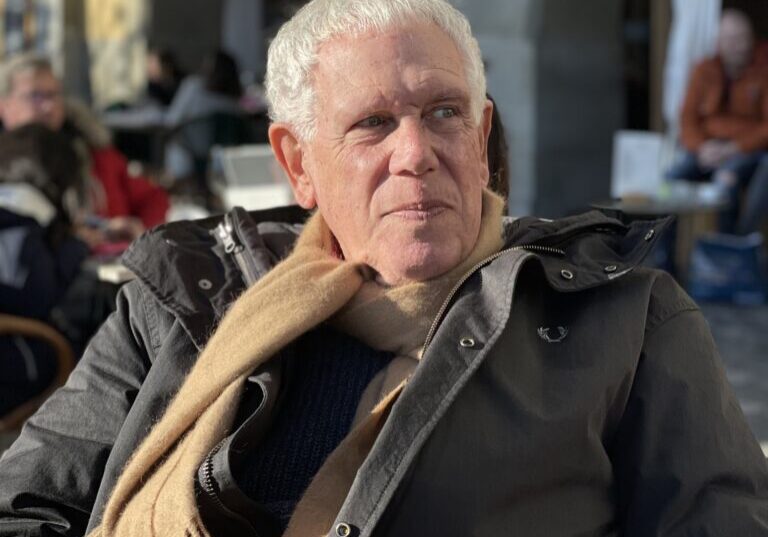 Older man wearing scarf at outdoor cafe